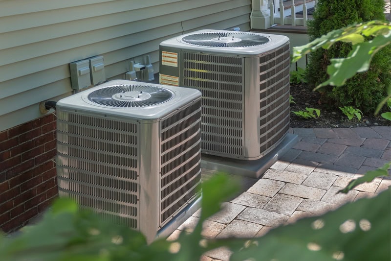 AC Definitions. Two HVAC units installed outside of a home or building.