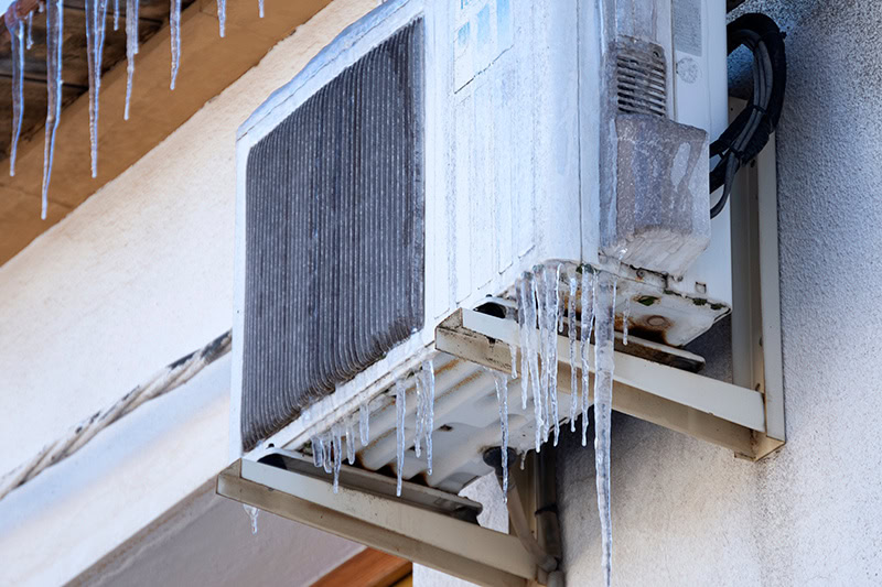 Why Is My Heat Pump Freezing Up? Photo of a heat pump frozen with icicles.